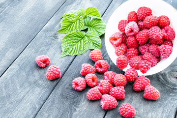 Fresh raspberry with leaves on the background of old dark boards. Selective focus.