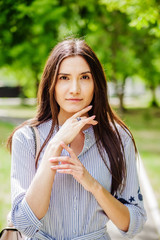 A girl of Asian appearance in a city park. Summer portrait of young Tatar on a background of green foliage