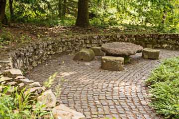 table made of stone and around the seat of stone in the garden, stone mur in the background