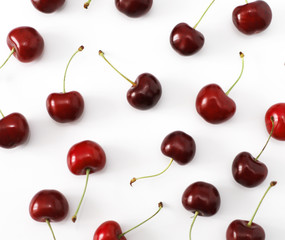 A bunch of ripe cherries with peduncles lies on a white background. Large collection of fresh red cherries. Ripe cherries background isolate