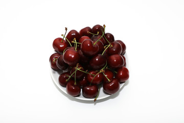 A bunch of ripe cherries with peduncles lies on a white background. Large collection of fresh red cherries. Ripe cherries background isolate