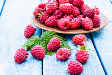Fresh raspberry with leaves on a blue boards background. Selective focus.