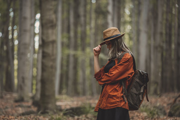 Style girl in hat with backpack in a summer time Mixed coniferous forest