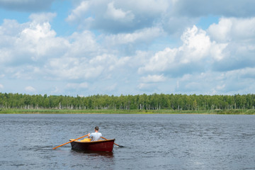a man is floating in a wooden boat on a lake on a nice sunny day, an active weekend