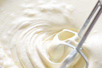 Whipping cream with a mixer. Bubbles on cream