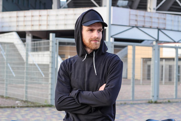 Charismatic man with red beard in a black cap and black hoodie. Street brand advertising. Fashion and style. Mockup.