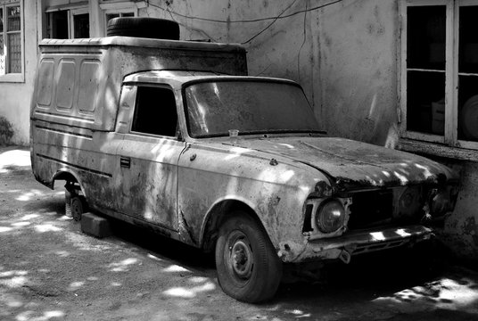 Black and white image of old, broken down car