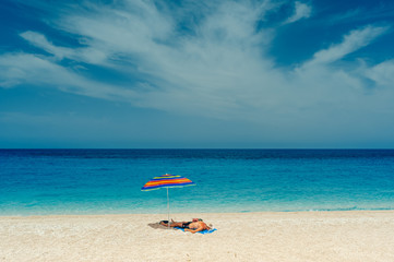 Retired man on sandy beach sunbathing on Mediterranean sea