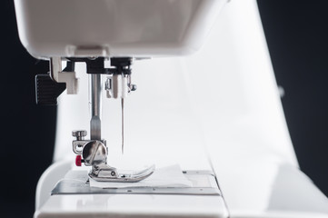 Needle Electromechanical white sewing machine close up on a black background, isolate