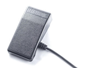 Black plastic pedal for the sewing machine with a wire on a white background, isolate