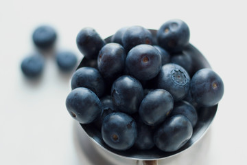 Healthy food. Diet berry. Blueberries closeup. A handful of berries lies in a metal bowl on a white background. Blue toned. Natural Vitamin C and antioxidants.