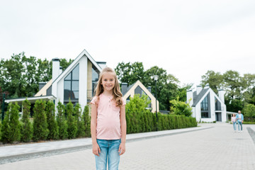 cheerful kid smiling white standing on street near houses