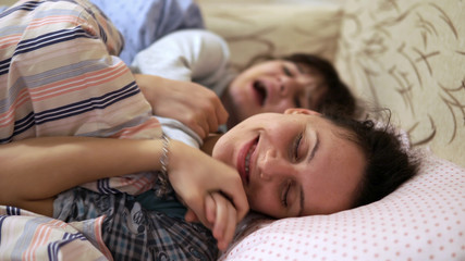 Obraz na płótnie Canvas Two teenage girls having fun fighting in bedroom.Sisters Relaxing Together In Bed Hugging