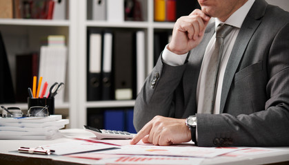 Businessman working and calculating, reads and writes reports. Office employee, table closeup. Business financial accounting concept.