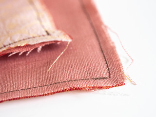 Close up of unravel pink-orange linen fabric texture with brown thread stitches with copy space....