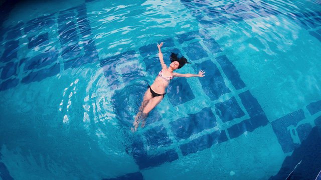 Directly Above Happy Female Swimming In A Pool. Aerial View