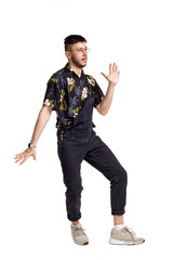 Full-length portrait of a funny guy dancing in studio isolated on white background.