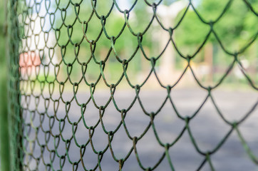 Old metal fence chain links on green background, metal mesh
