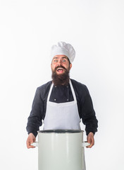 Cook in chef uniform holds saucepan. Male chef. Kitchen utensils concept. Chef in white apron with casserole or saucepan. Cook in white hat and apron holds soup pot. Cuisine, cooking, food preparation