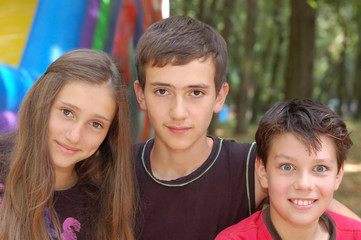 The three best friends - two brothers and sister together have a rest in the park in the summer....