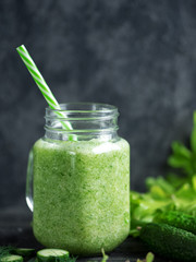 Green cucumber smoothie for weight loss in a glass on a wooden dark table with ingredients