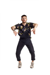 Full-length portrait of a funny guy dancing in studio isolated on white background.