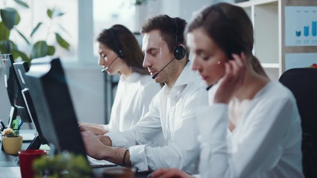Close up view of group of young business people with headset working and giving support to customers in a call center office. Working hard, team, business. Profession and workplace concept
