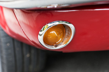 View of a orange direction light from an old red car
