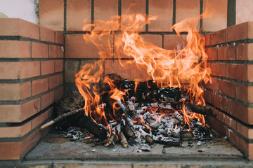 A beautiful bonfire in the barbecue. The wood are burning between the flames. Close up and selective focus. Background.