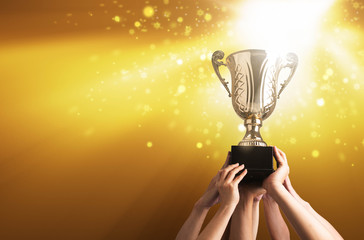 Winning team raise trophy cup with background of sky of light ray