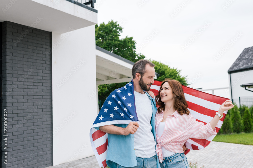 Wall mural happy bearded man standing with attractive woman and holding american flag