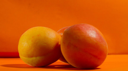 Ripe juicy apricot fruit on an orange background