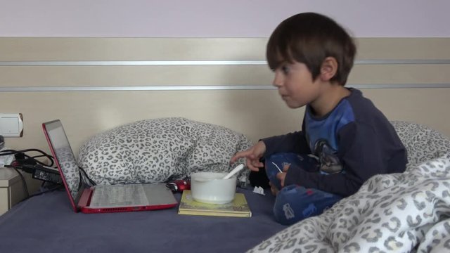 4K Child fiddles around in front of PC notebook and a bowl with food