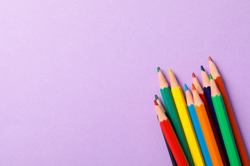 Multicolor pencils on violet background, space for text