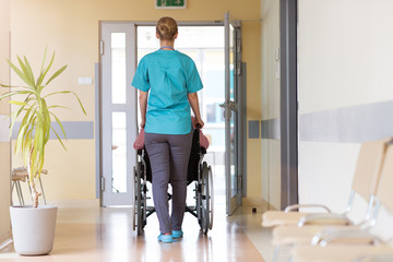 Senior woman in wheelchair with nurse in hospital