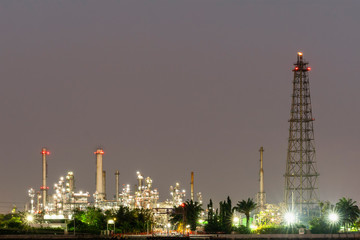 Night photo crude oil refinery plant and many chimney at coast of the river with colorful bright light from lamp at thailand