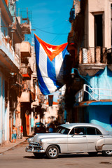 Obraz na płótnie Canvas Antique car and cuban flag in Old Havana