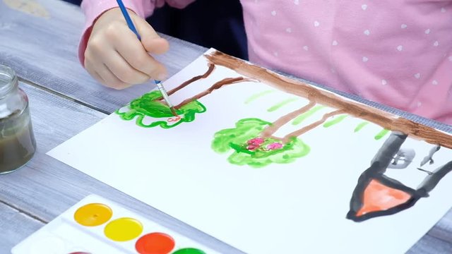 the child paints on a white sheet of paper