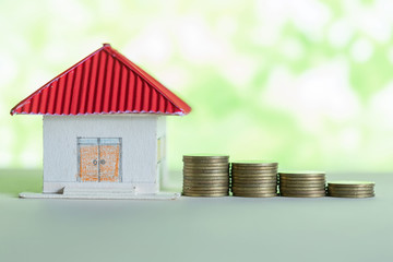 Model of house with coins on wooden table, saving money for buy home concept