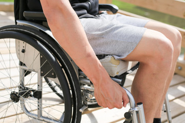 Obraz premium Disabled young athletic man on a wheelchair holding and turning wheels with hand engage in sports
