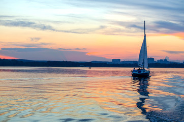 Obraz na płótnie Canvas Scenic sunset over the river with sailing yacht