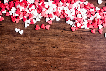 Valentines Day background with red and white hearts on a wooden table, top view. Red heart shaped candies on a wooden brown background. The concept of Valentines Day. 