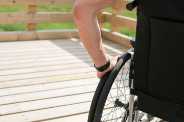 Obraz premium Disabled young man on a wheelchair holding and turning wheels with hand