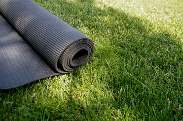 Yoga mat on a grass background. Equipment for yoga. Concept healthy lifestyle. Lots of copyspace