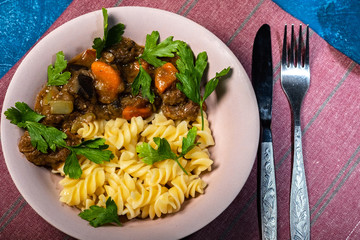 beef stew with vegetables and pasta spiral with greens