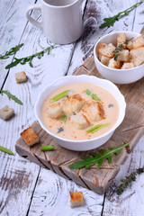 Cream soup with croutons, green onion and cheese in a white bowl