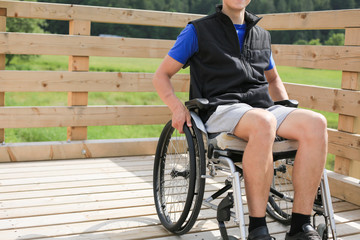 Obraz premium Disabled young man on a wheelchair holding and turning wheels with hand
