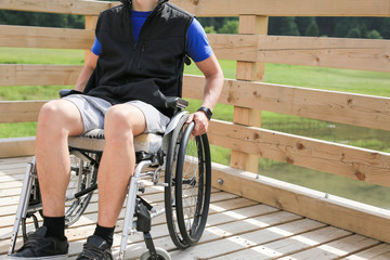 Disabled young man on a wheelchair holding and turning wheels with hand