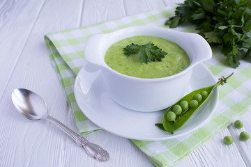Pea soup  in the white bowl on the white wooden background.Closeup.