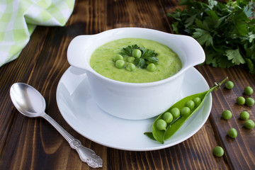 Pea soup  in the white bowl on the brown  wooden background.Closeup.